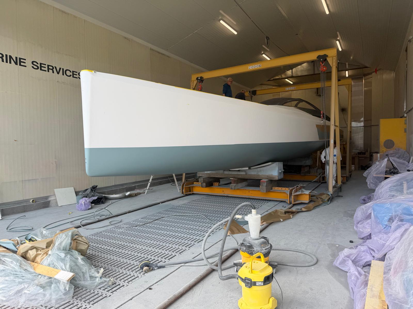 Guerrera's hull on its cradle inside the refit shed, crew working on the gantry above